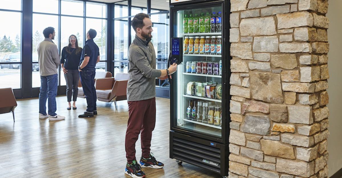 Employee buying a drink from a smart vending cooler in an office lobby